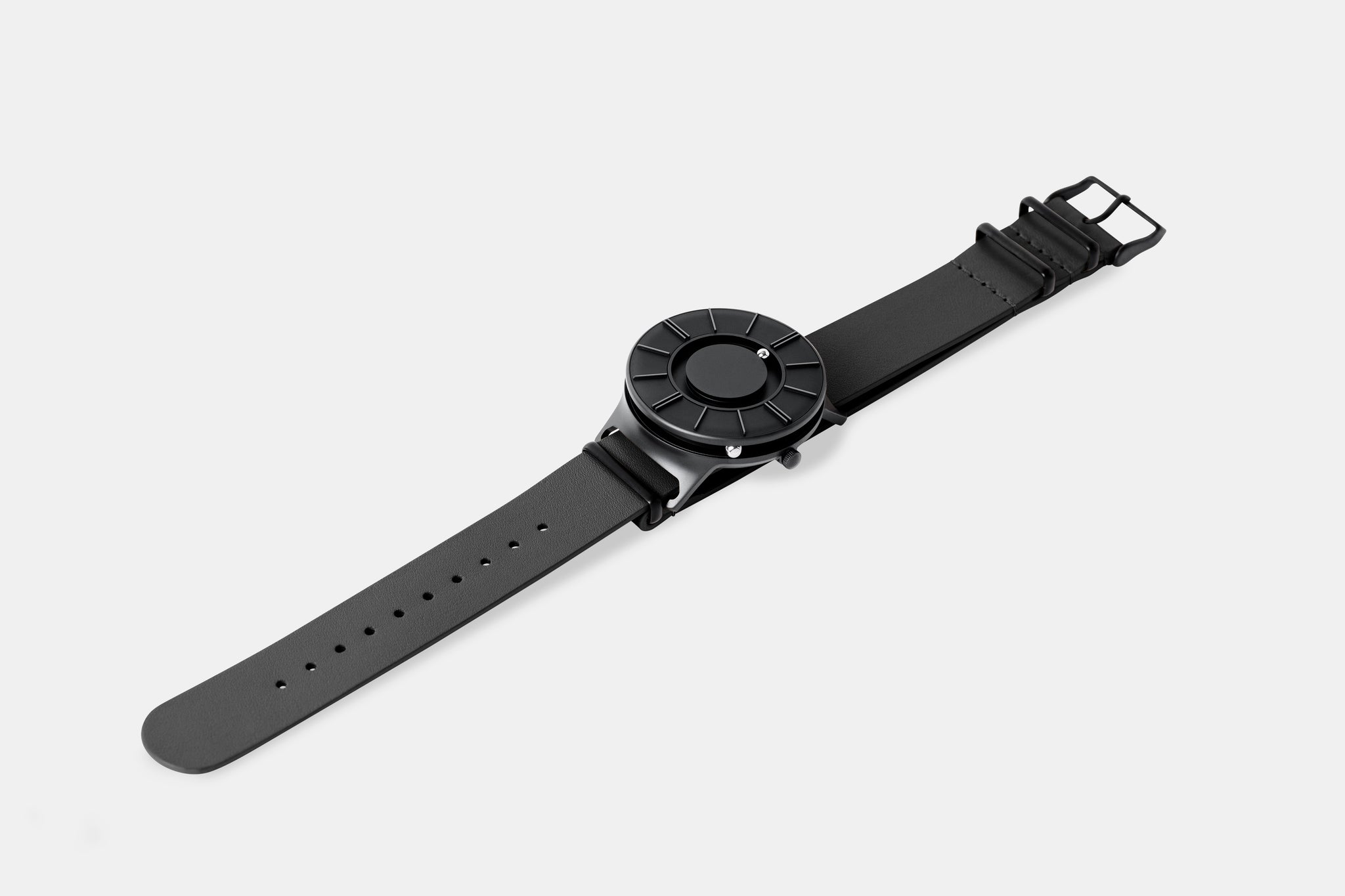 A photo of the watch lying flat on a surface. The recessed track around the outside of the watch face is shown with the hour ball bearing in the track. The raised markers are noticeable from this perspective.