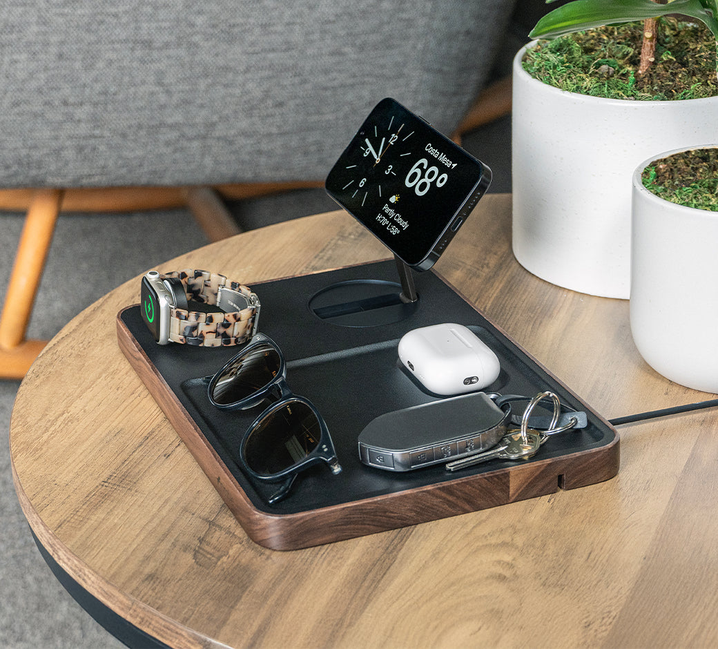 Smartphone and smart watch on wireless charger with green charging indicator.