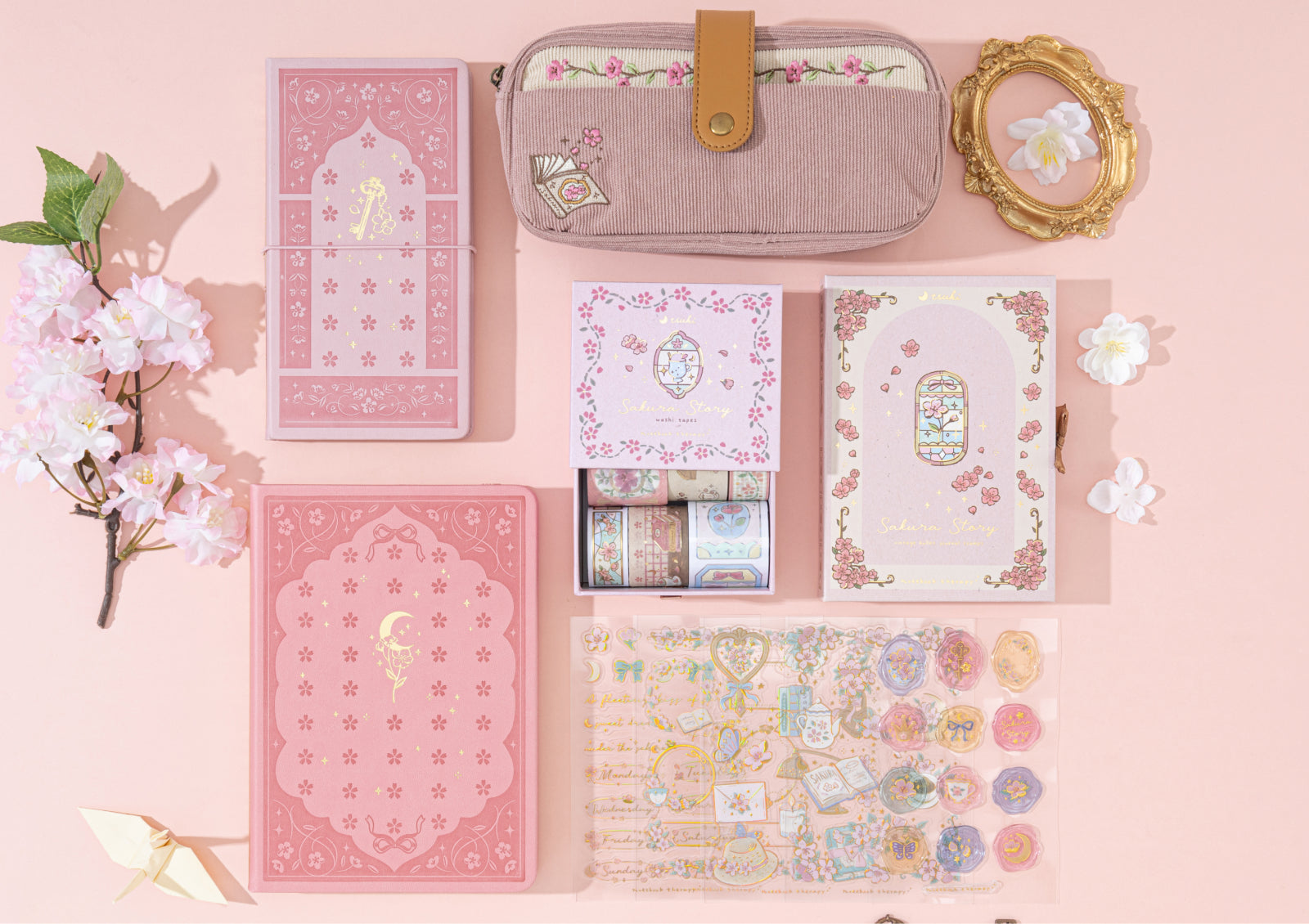 A flat lay arrangement of the complete Sakura Story stationery collection, including journals, stamps, washi tapes, and a corduroy pencil case.