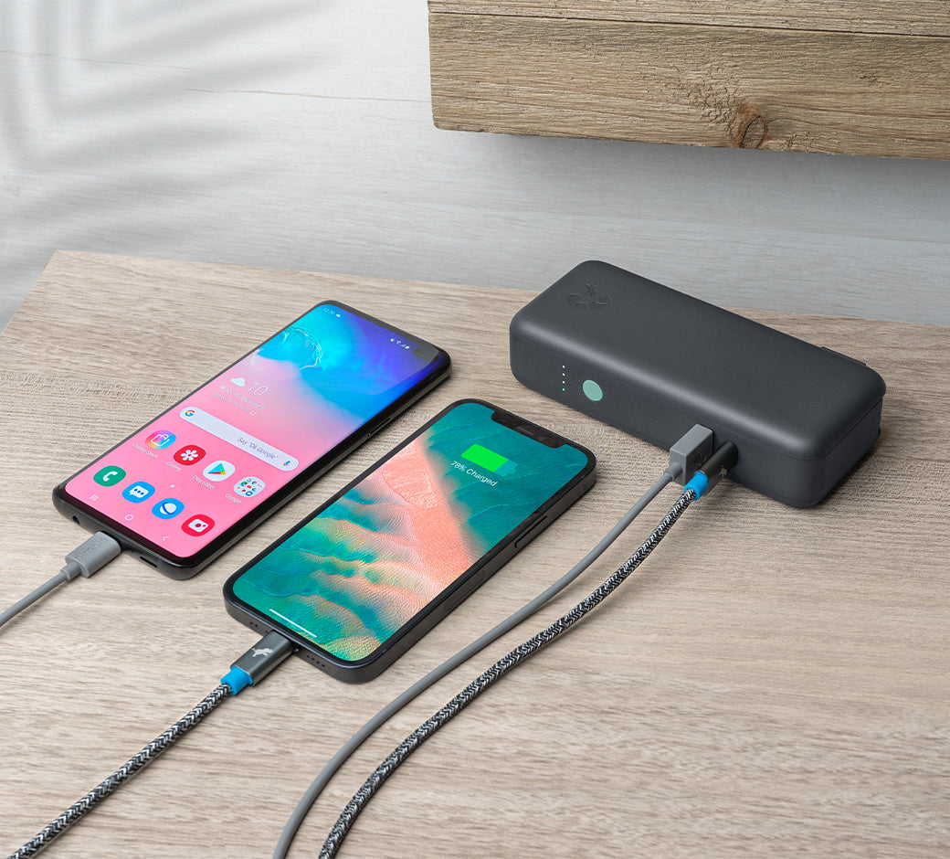 Portable charger, smartphone, earbud case, and cable arranged neatly on a laptop.