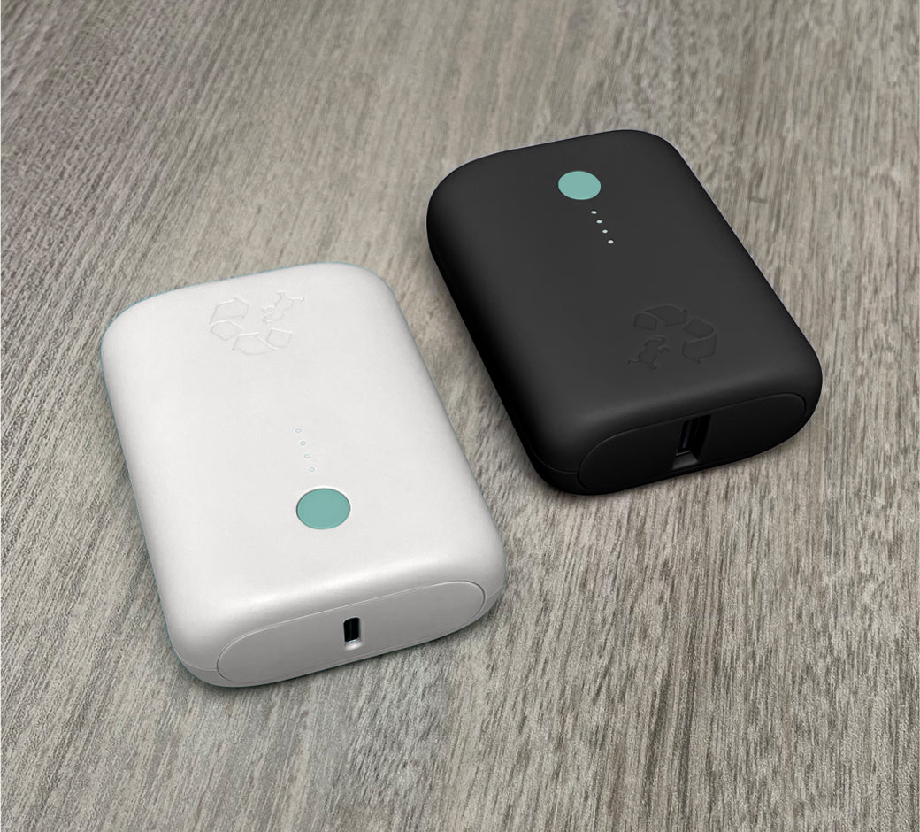 White and black compact power banks with recycling logos on a gray textured surface.